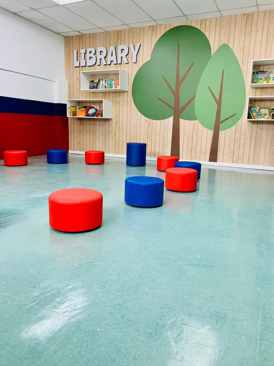 Biblioteca com árvores ilustradas e pufes coloridos